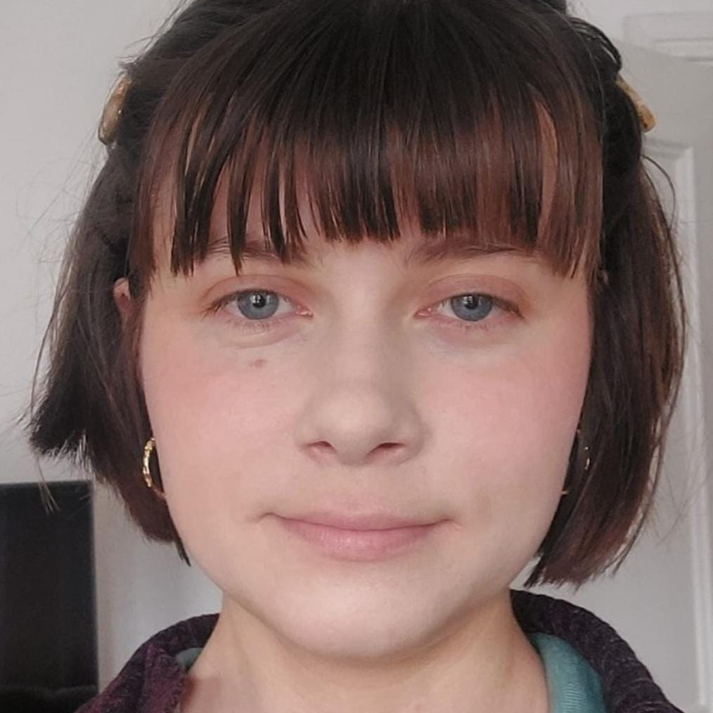 A woman called Heledd C Evans is looking directly towards the camera with a slight smile. She has brown bobbed hair with a fringe. She is wearing gold hooped earrings. It is a close-up image of her face.