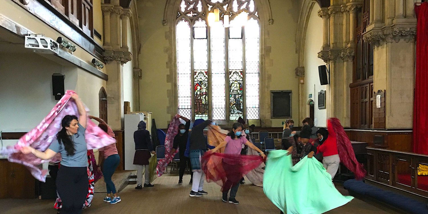 Women dancing with sheets of fabric inside a church.