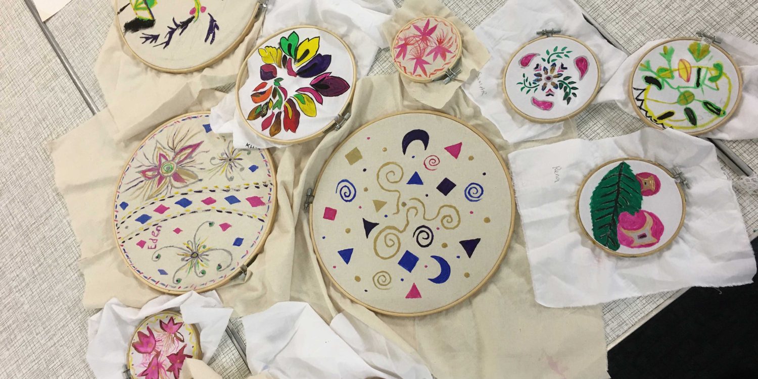 Embroidery frames of different sizes displaying painted fabric.