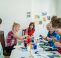 A group of women are sat around a table monoprinting.