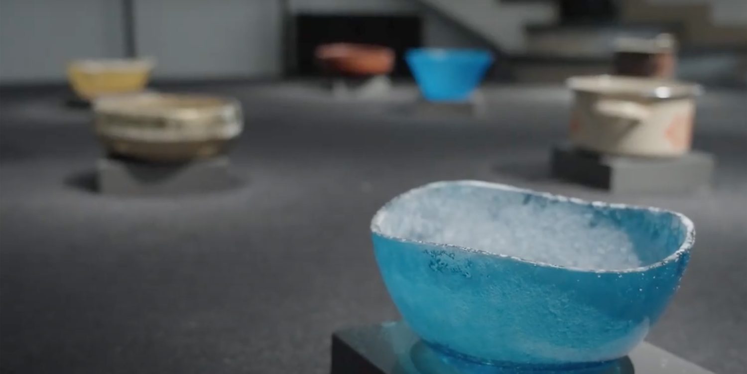 Coloured bowls on the gallery floor are positioned to collect water dripping from roughly cut pieces of salt suspended in nets above.