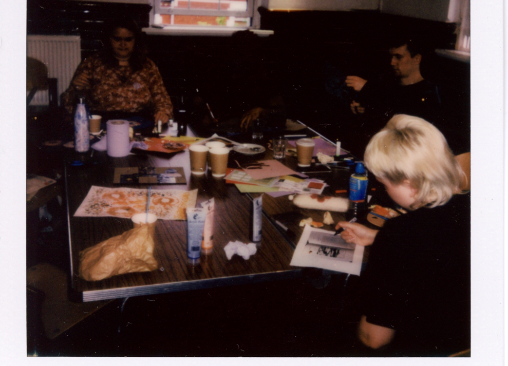 A polaroid of people sat around a table, taking part in a creative workshop.