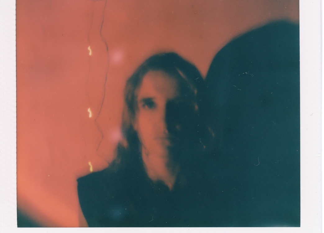 A blurry polaroid of a person with long hair.